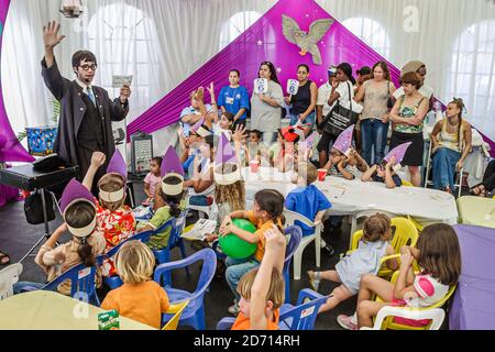 Miami Florida,International Book Fair festival,man magician perfoms performing magic trick tricks,children watch boys girls kids audience, Stock Photo