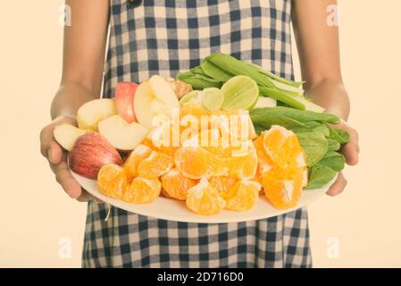 Woman holding different kinds of fruits and vegetables served on white plate with healthy lifestyle concept Stock Photo
