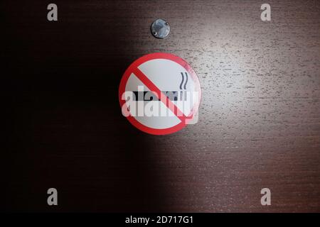 No smoking sign stuck on the wooden door of the hotel room. The crossed out cigarette. Concept signs, rules of conduct in public places, comfort, heal Stock Photo