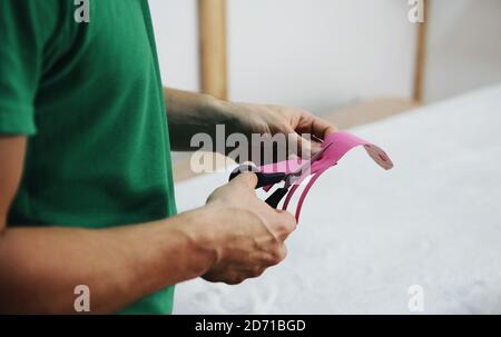 Close up view of doctor's hands with scissors that cuts pink kinesio tape Stock Photo