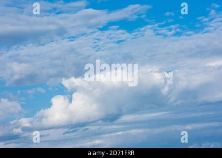 Large clouds and storm clouds close-up against a blue sky. White clouds are mixed with thunderclouds. Stock Photo