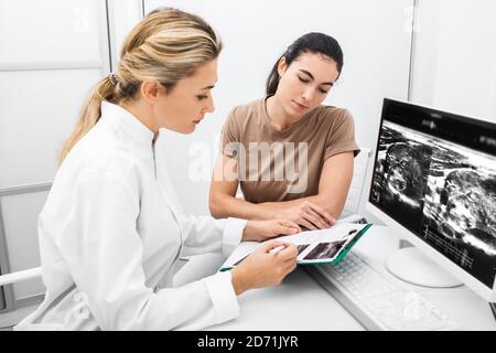 Endocrinologist consulting the woman, doctor analyzes the ultrasound of the patient's thyroid gland. Treatment of thyrotoxicosis, and hypothyroidism Stock Photo