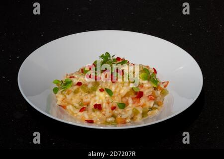 Tomato risotto with buffalo mozzarella and dwarf basil leaves on a white plate Stock Photo