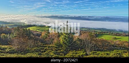 View from western slopes of Pennycloddiau Mountain in the Clwydian Range in morning light with low cloud streaming down the Vale of Clwyd  North Wales Stock Photo
