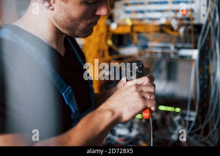 Young man in uniform works with internet equipment and wires in server room Stock Photo