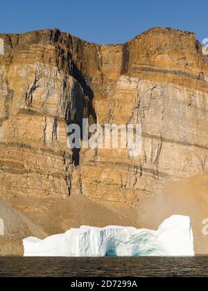 Landscape with steep yellow cliffs and icebergs in the  Uummannaq fjord system in the north of west greenland.  America, North America, Greenland, Den Stock Photo