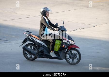 SAMUT PRAKAN, THAILAND, JUL 29 2020, A woman rides a motorcycle with box on a floor. Stock Photo