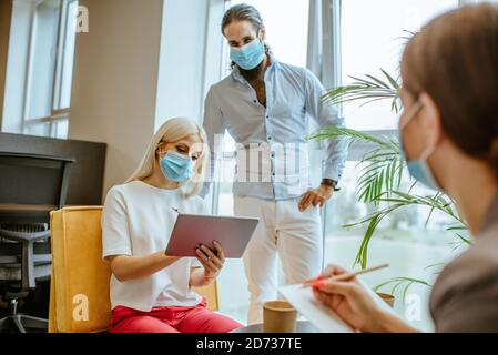 Business people in protective medical masks discussing Stock Photo