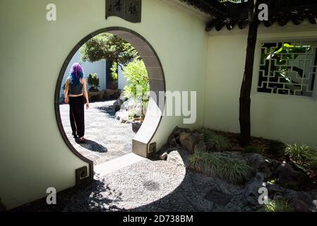 Person walks through a round doorway in a wall at Lan Su Chinese Garden, Portland, Oregon, USA. Stock Photo
