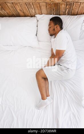 African American Guy Sleeping Lying In Bed At Home, Top-View Stock Photo
