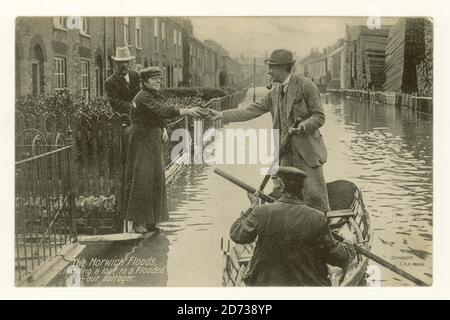 Early 1900's postcard of flooded streets in Norwich on 26 August 1912 entitled 'handing a loaf to a flooded-out cottager', Lothian Street with Cushions woodyard on right Stock Photo