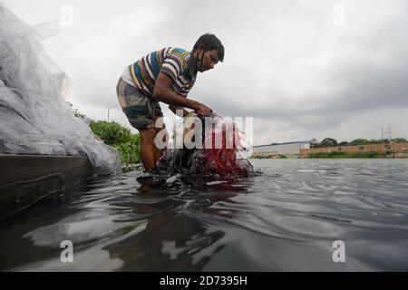 A Bangladeshi man washes plastic waste, which were used to carry chemicals, in the water of the Turag River before recycling it, in Tongi, near Dhaka,