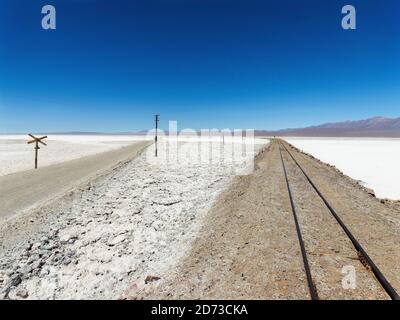The salt flats Salar de Pocitos in the  Argentinian Altiplano. Routa 27 and the railway Salta - Antofagasta is crossing the salt flats. South America, Stock Photo