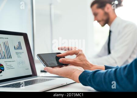 close up. employee is using his smartphone to check the financial data . Stock Photo