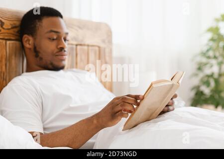 African American Man Reading Books Enjoying Morning Sitting In Bed Stock Photo