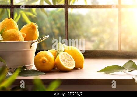 Basket full of lemons on kitchen with a window and a lemon grove in the background. Front view. Horizontal composition. Stock Photo