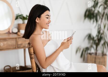 Beautiful asian lady using smartphone in bedroom Stock Photo