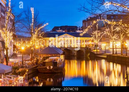 Ancient view of the Dutch Oude Rijn canal with bridge, historic buildings and christmas lights in the city center of Leiden, The Netherlands Stock Photo