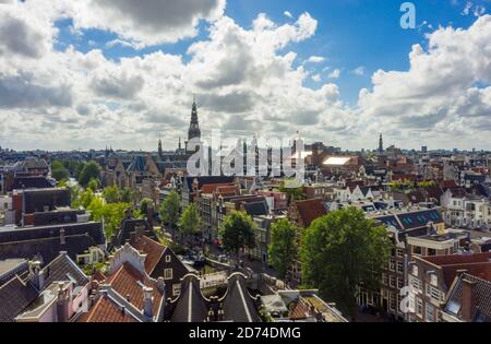 Beautiful Amsterdam Cityscape from Aerial rooftop perspective above Canals and Church Tower View with Blue Sky and big clouds Stock Photo