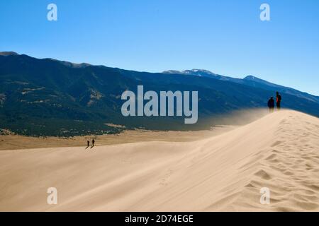 Hiking and Sand Boarding in Tallest Sand Dunes in North America. Great Sand Dunes National Park. Sangre de Cristo Mountains in Colorado, USA Stock Photo