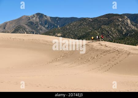 Hiking and Sand Boarding in Tallest Sand Dunes in North America. Great Sand Dunes National Park. Sangre de Cristo Mountains in Colorado, USA Stock Photo