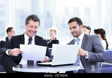 business partners discussing a new project, sitting in the lobby of the office. Stock Photo