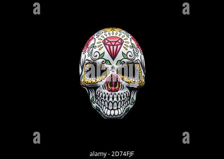 Halloween mask representing a traditional mexican skull with colorful floral pattern isolated on a black background. Stock Photo