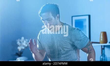 Close Up of a Strong Athletic Fit Man in T-shirt Concentrated on Energetical Jogging at Home in His Spacious and Bright Apartment with Minimalistic Stock Photo