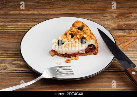 Piece of cake with cottage cheese souffle and plum decorated with almonds and blueberries on wooden table Stock Photo
