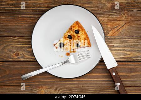 Piece of cake with cottage cheese souffle and plum decorated with almonds and blueberries on wooden table. Top view. Stock Photo
