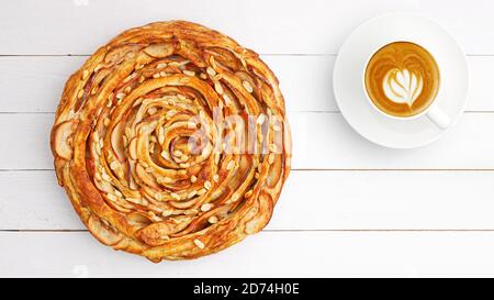 Fresh baked homemade puff pastry swirl pie with apple, cinnamon and peanut on white wooden table. Top view. Copyspace. Stock Photo