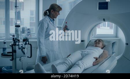 In Medical Laboratory Female Radiologist Controls MRI or CT or PET Scan with Female Patient Undergoing Procedure. Doctor Conducts Emergency Scanning Stock Photo