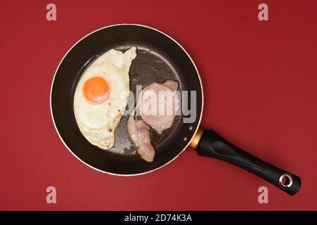 Fried egg and bacon in a pan Stock Photo