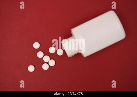 pills and a pill bottle isolated on a red background Stock Photo