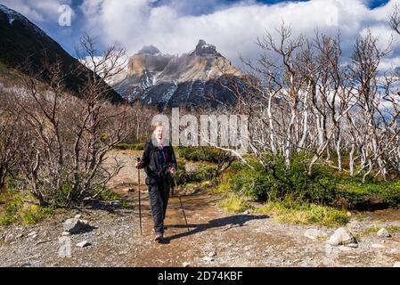 Couple trekking in Torres del Paine National Park with Los Cuernos and the Paine Massif behind, Patagonia, Chile Stock Photo