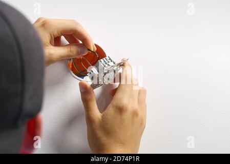 electrician installing light switch on painted wall with screwdriver. Man installing light switch after home renovation. Stock Photo