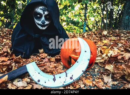 Young woman with halloween paint face mask wearing black hood Stock Photo