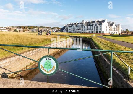 View over the Barry Burn towards the Carnoustie Hotel and golfers walking along the first fairway on the Carnoustie Championship links golf course, Stock Photo