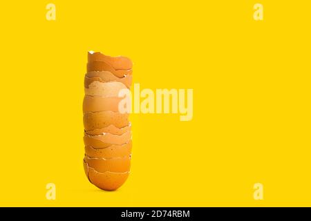A heap of cracked eggshells on a yellow background in a close up view Stock Photo