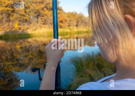 Young woman fisherman holds fishing rod hook with live bait. Fishing with a worm. Stock Photo