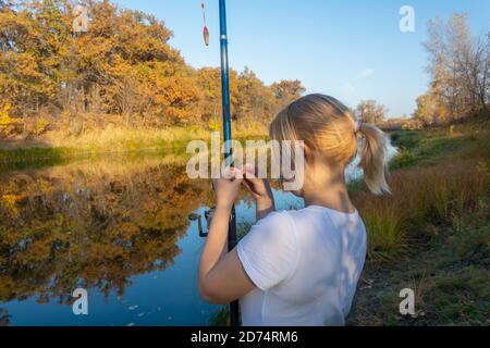 Fishermans hand holding a fishing lure on the hook above the lake