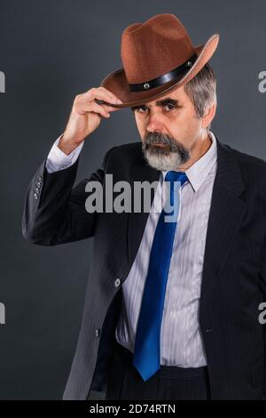 Elderly dandy man in a suit with a tie takes off his hat for a greeting Stock Photo