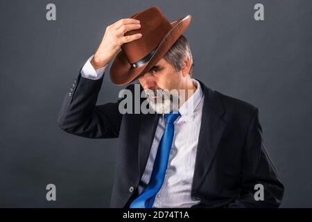 Elderly dandy man in a suit with a tie takes off his hat for a greeting Stock Photo