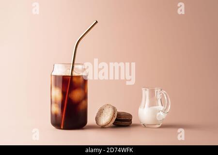 Glass of iced coffee in tall glass with golden straw with cream and macaroons chocolate, vanilla on pastel background for your design. Food concept in vintage style. Copy space. Closeup. Stock Photo
