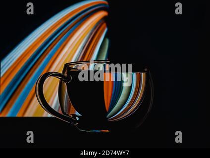 Abstract colorful refraction in transparent glass of water on isoleted black background for concept design. Optical illusion concept. Closeup. Copy space. Stock Photo