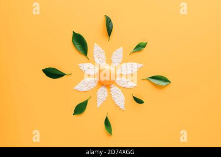 Flower made of yolk, cracked egg shell and fresh green leaves in abstract style on soft yellow background. Organic meal concept. Abstract background. Mockup for your design. Flat lay style. Stock Photo