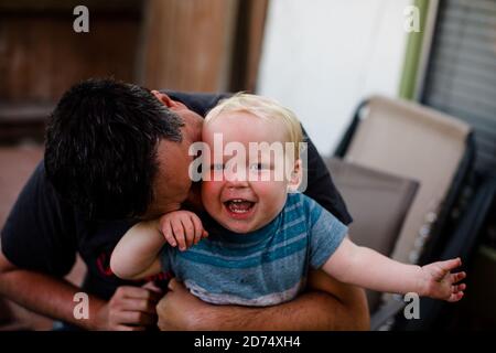 Uncle Holding Laughing Nephew in Yard in San Diego Stock Photo