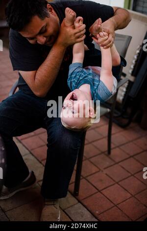 Uncle Holding Nephew Upside Down in Yard in San Diego Stock Photo