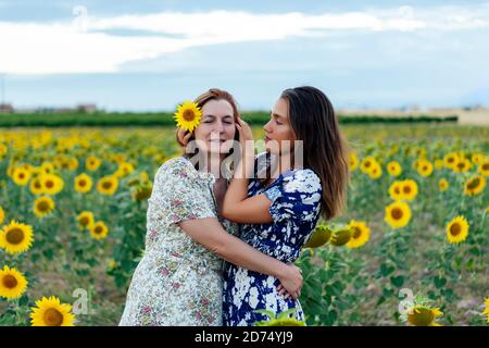mother and daughter hugging and kissing in a field of sunflowers Stock Photo