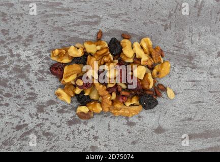 Top view of a portion of nuts and dried fruits trail mix on a gray background. Stock Photo